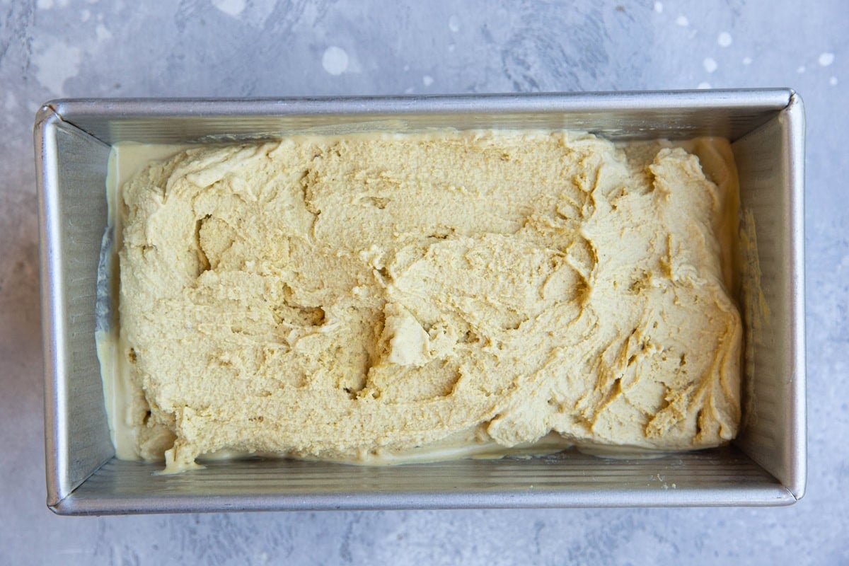 Loaf pan with pistachio ice cream mixture inside, fresh out of the ice cream maker and ready to freeze.