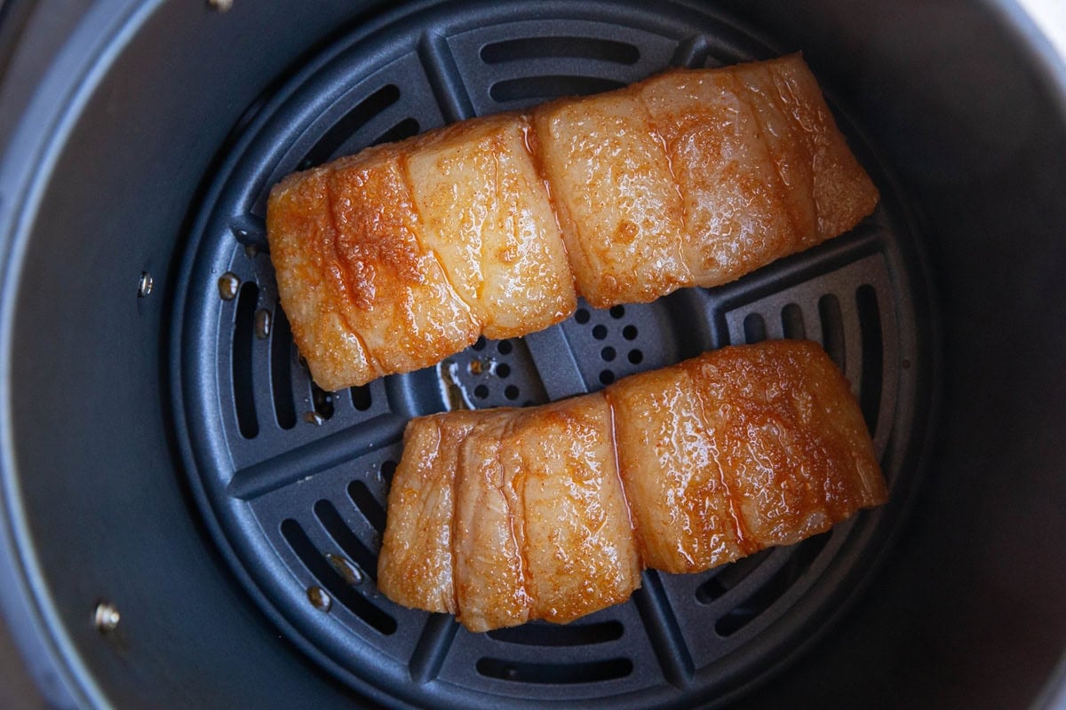 Marinated halibut in the basket of an air fryer, ready to be cooked.