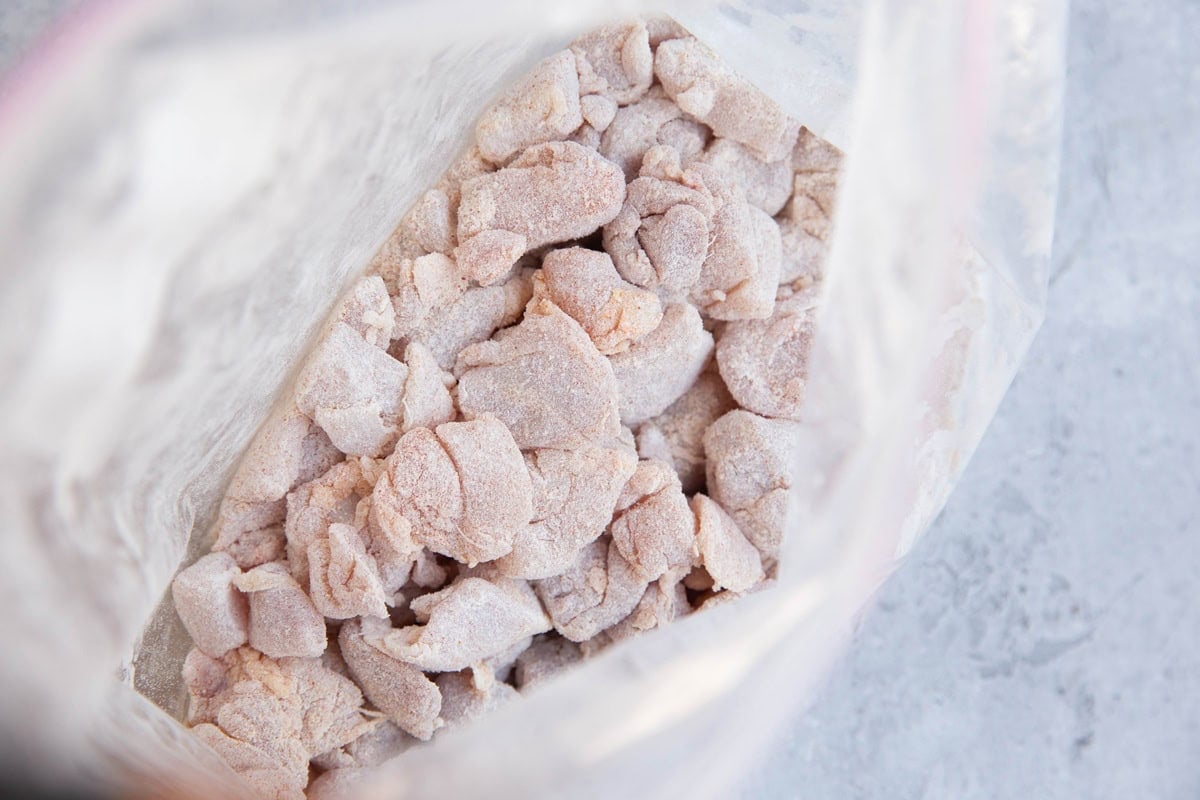 Zip lock bag full of chopped chicken pieces tossed in flour and seasonings.