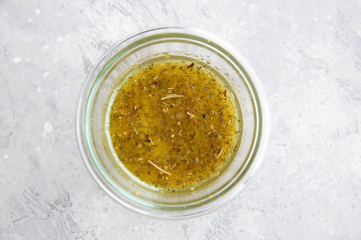Small bowl of Greek salad dressing to use on couscous salad.