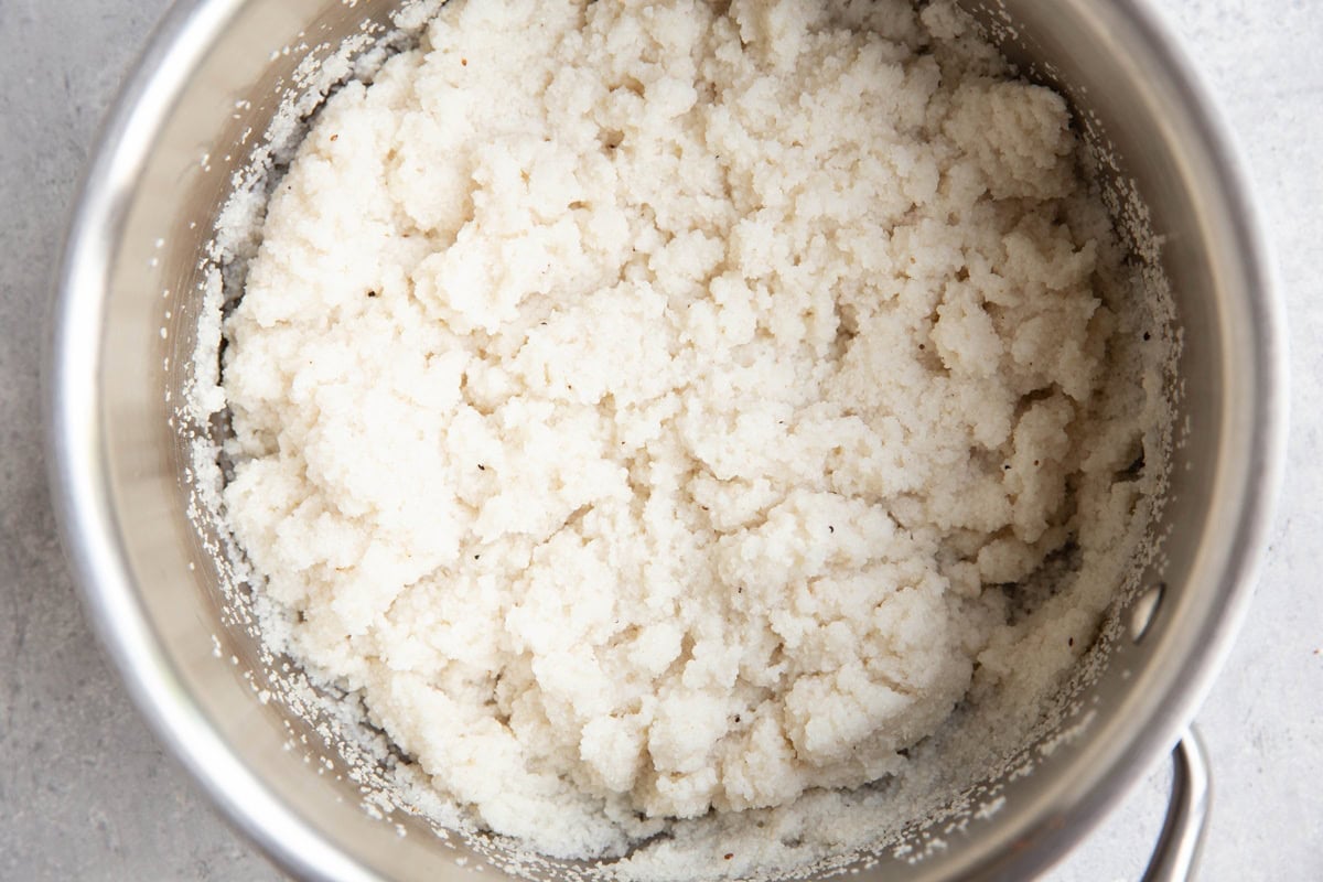 Stainless steel pot full of cooked couscous.