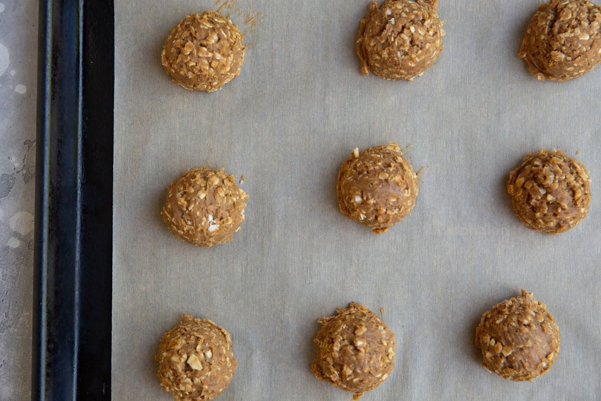 9 balls of oatmeal cookie dough on a baking sheet. Ready to go into the oven.