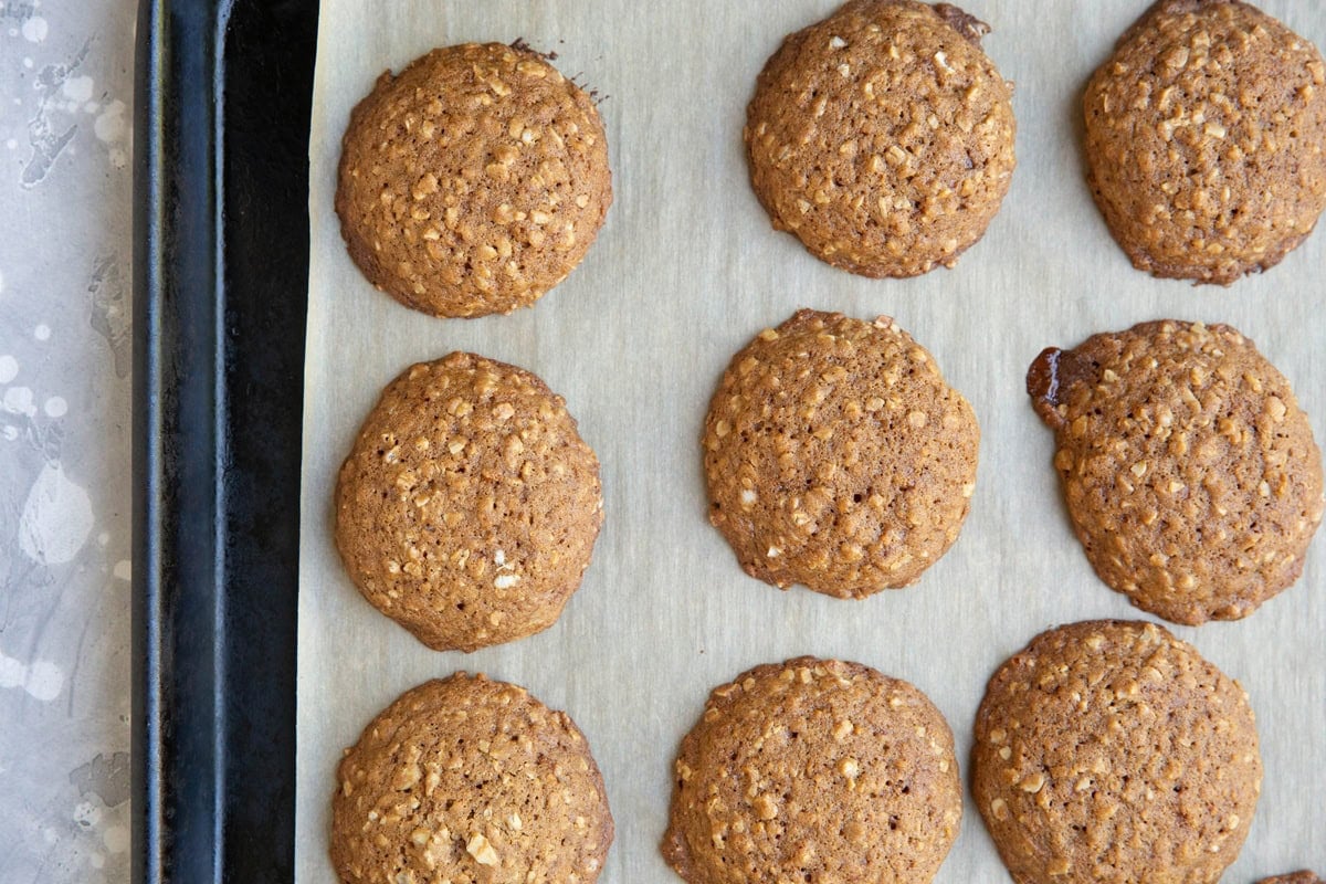 Baking sheet of nine oatmeal cookies fresh out of the oven and golden brown.