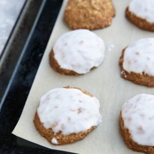 Baking sheet with iced oatmeal cookies on top of a sheet of parchment paper. Ready to serve.