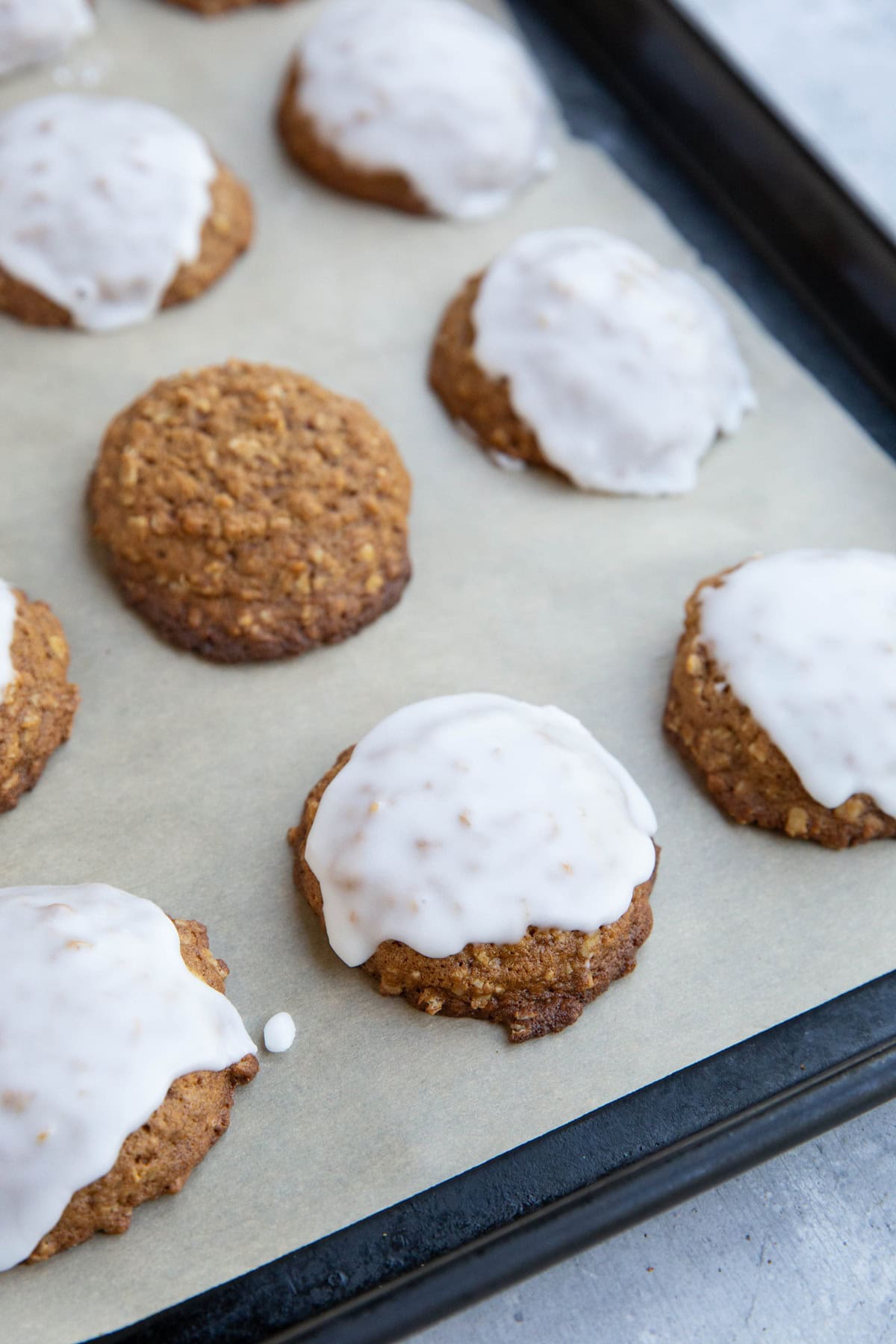 Baking sheet full of iced oatmeal cookies, ready to enjoy.