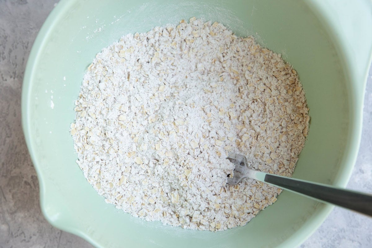 Mixing bowl with flour and oats stirred together with a fork.