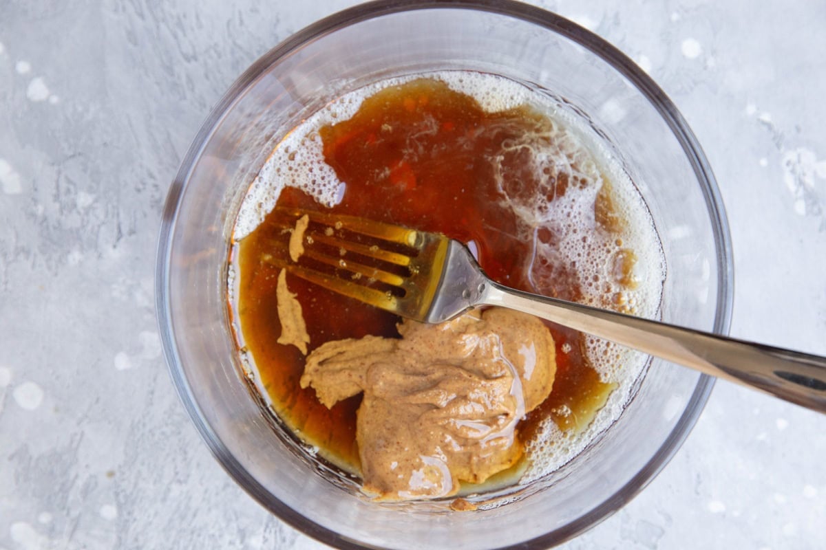 Egg white, almond butter, pure maple syrup, and vanilla extract in a bowl to be whisked together.
