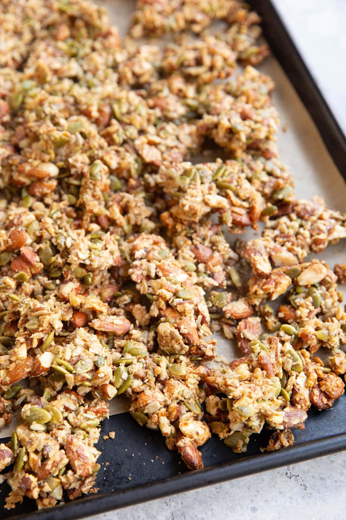 Rimmed baking sheet with granola clusters spread over it, ready to eat.