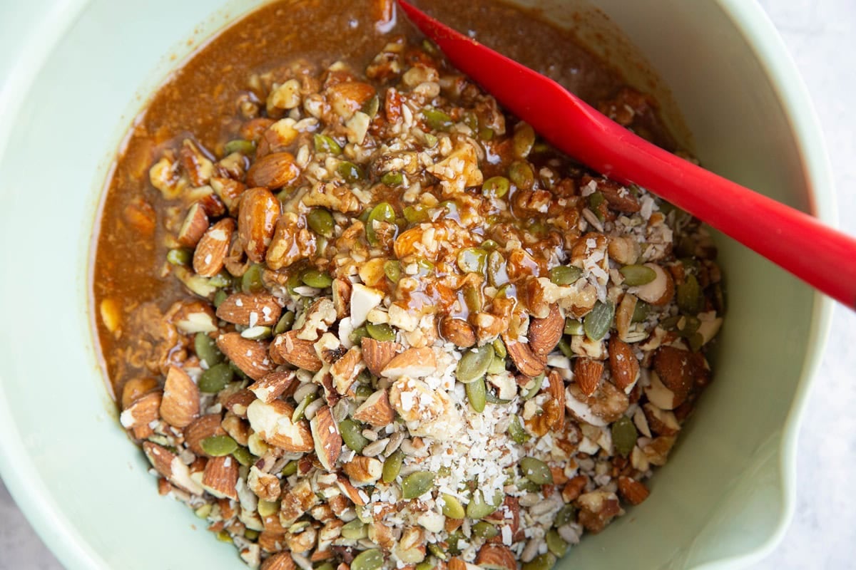 Nuts, seeds, and egg white mixture in a mixing bowl to make homemade granola.