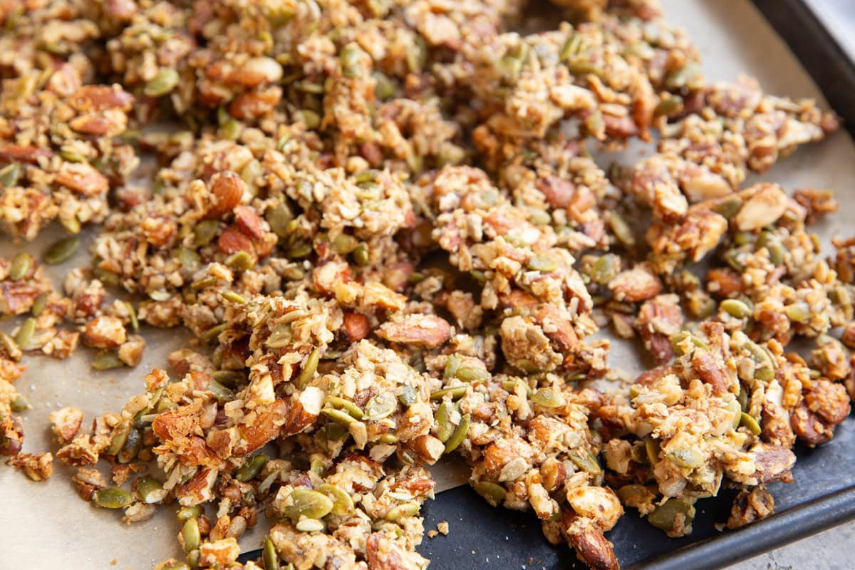 Baking sheet with homemade granola fresh out of the oven. Th clusters are large and appear crunchy.
