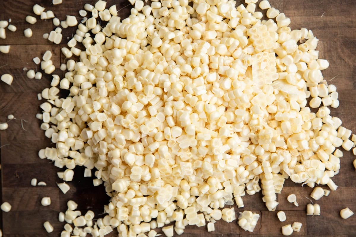 Fresh corn kernels on a wooden cutting board, ready to use in a recipe