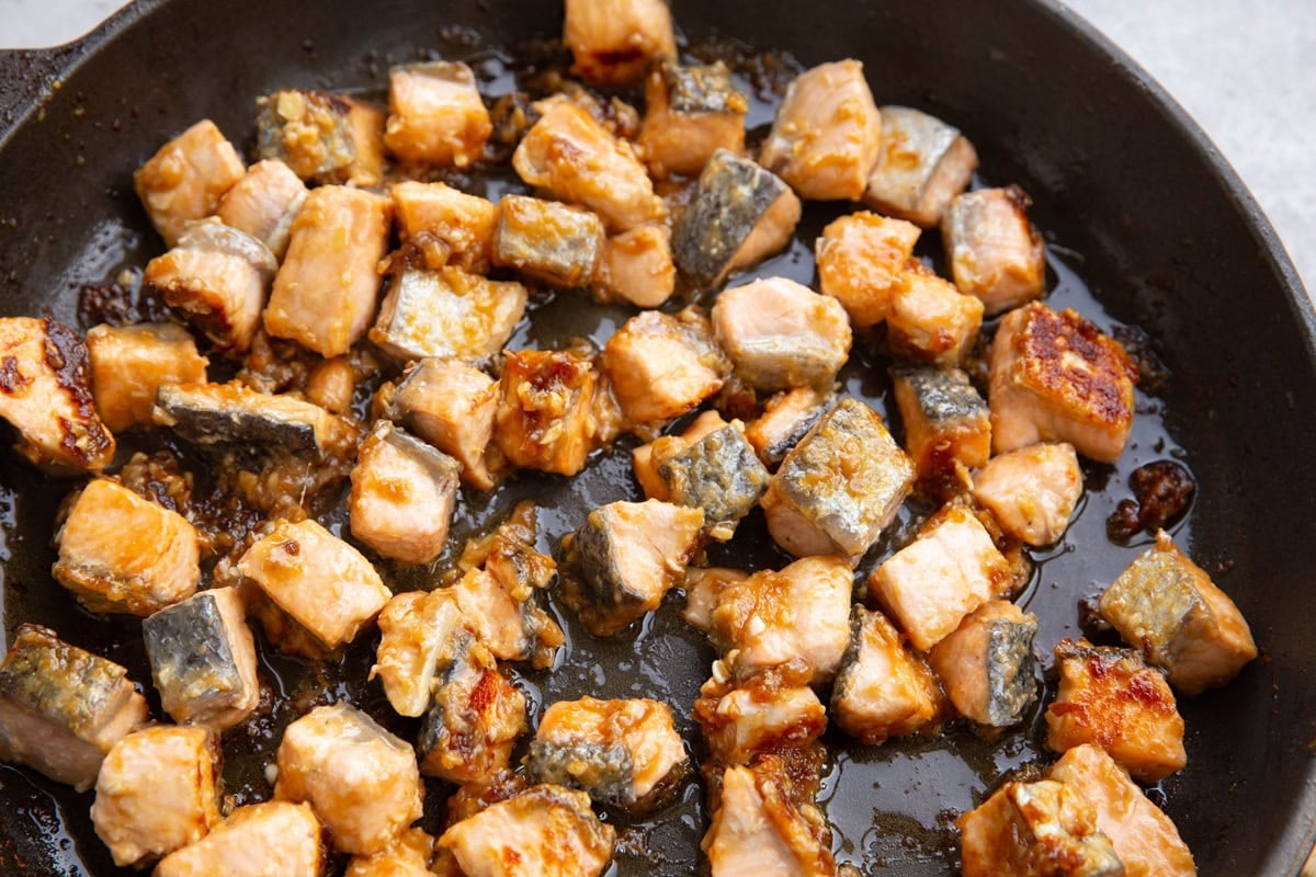 Skillet full of chopped salmon with sauce cooking.
