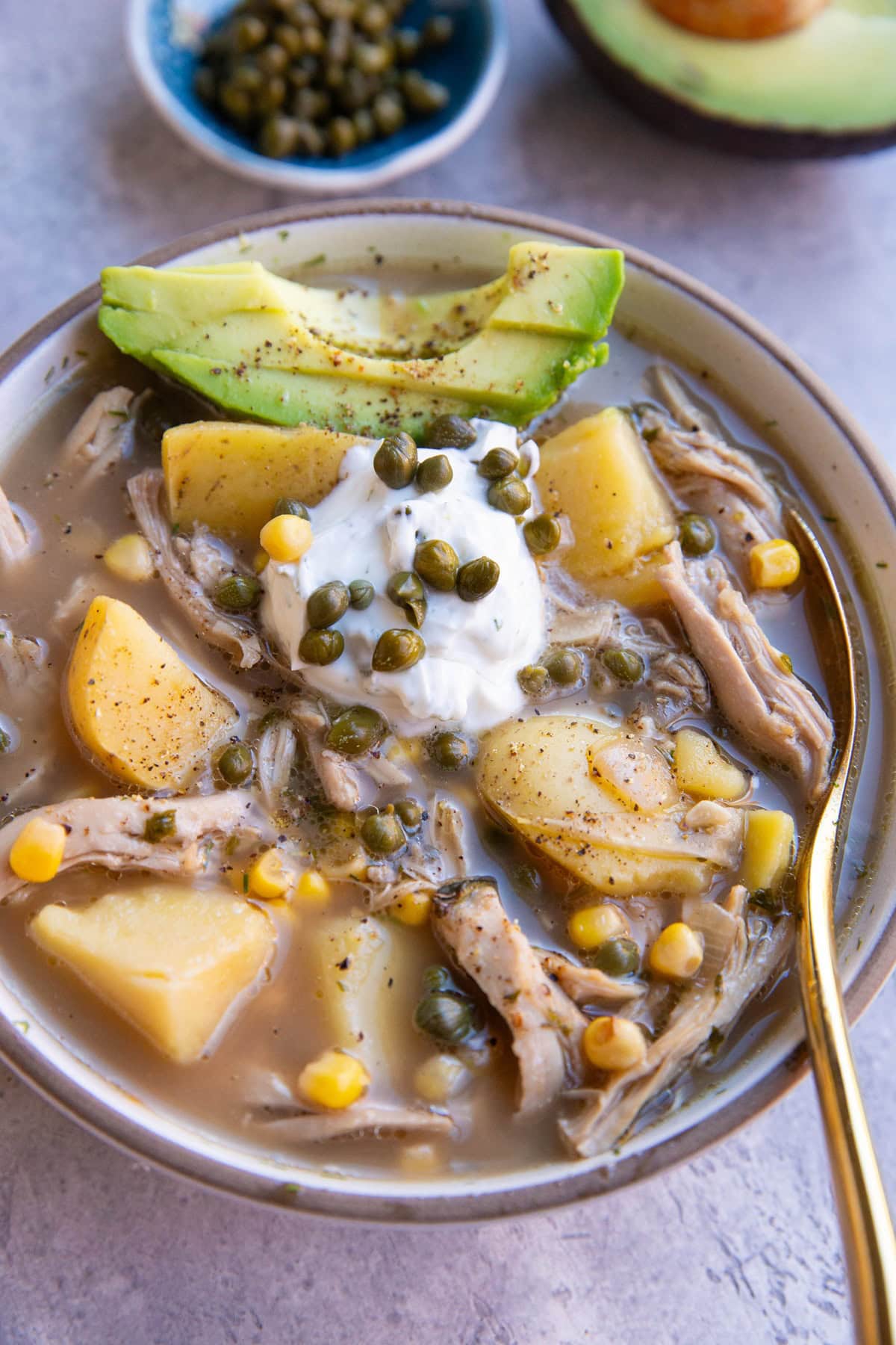 Bowl of chicken and potato soup with corn and sliced avocado with Greek yogurt on top.