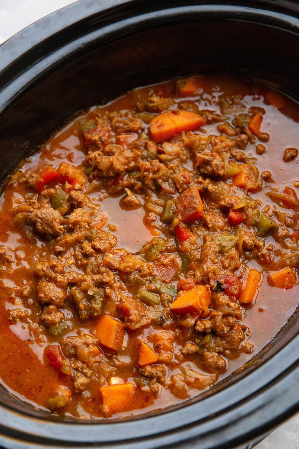 Slow cooker full of beef, pumpkin, and sweet potato chili, fully cooked and ready to serve.