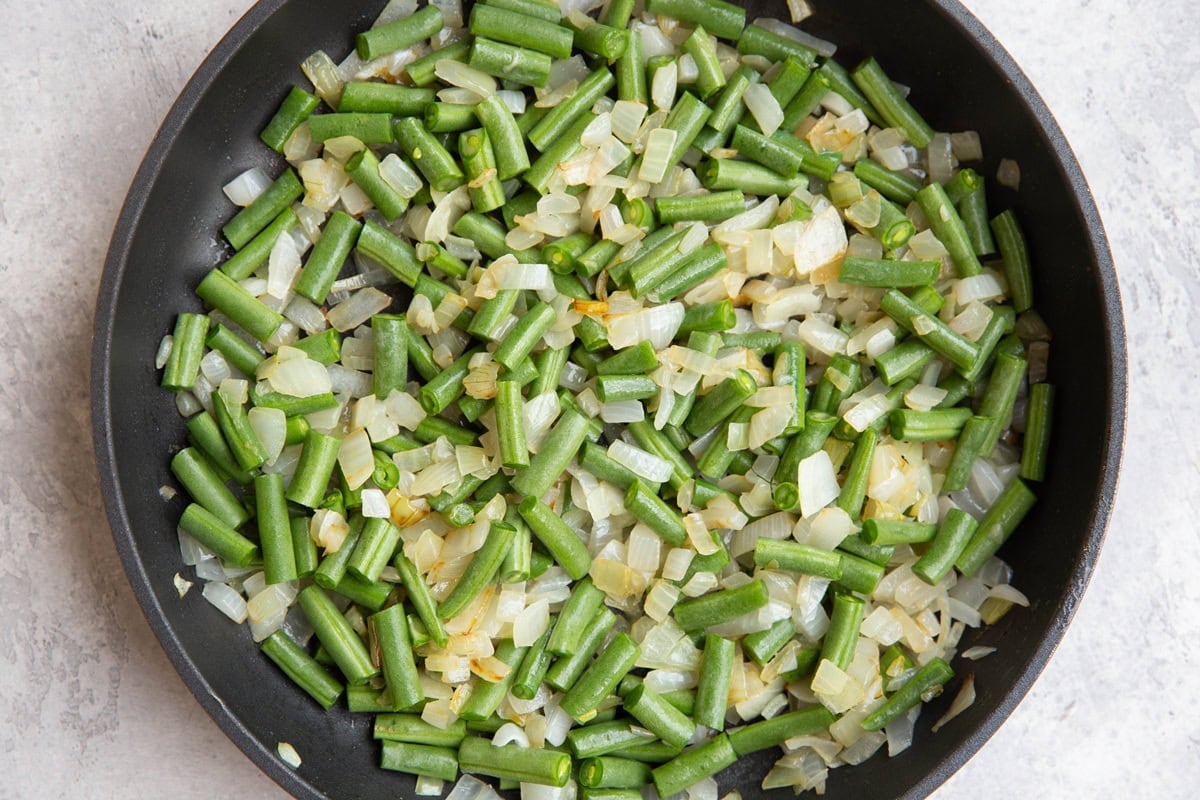Skillet of sauteed onion and green beans.