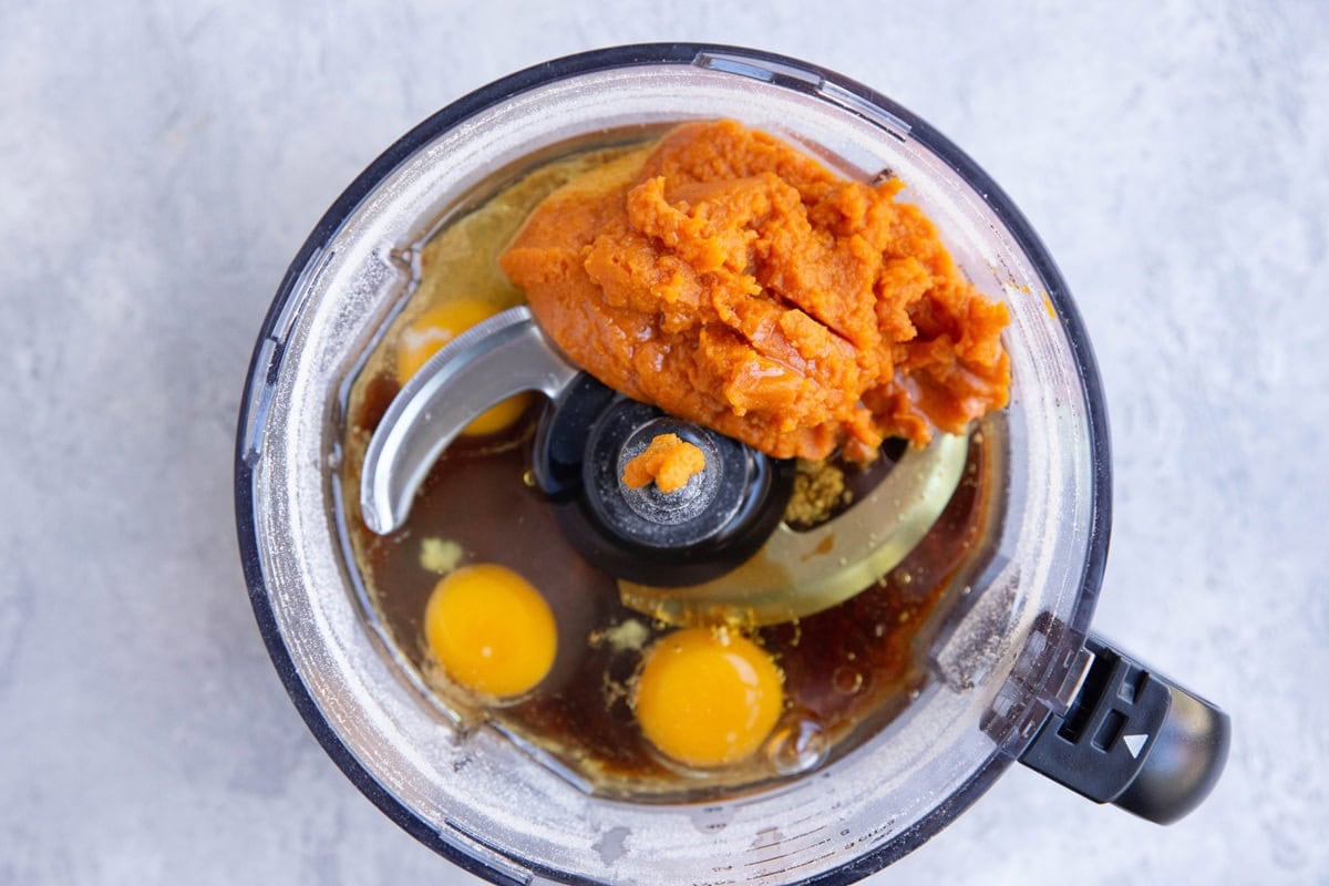 Food processor with ingredients for pumpkin breakfast cake inside.