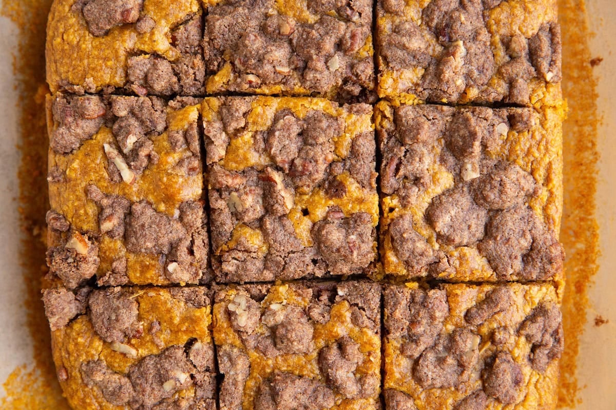 Pumpkin streusel cake cut into slices on a sheet of parchment paper.