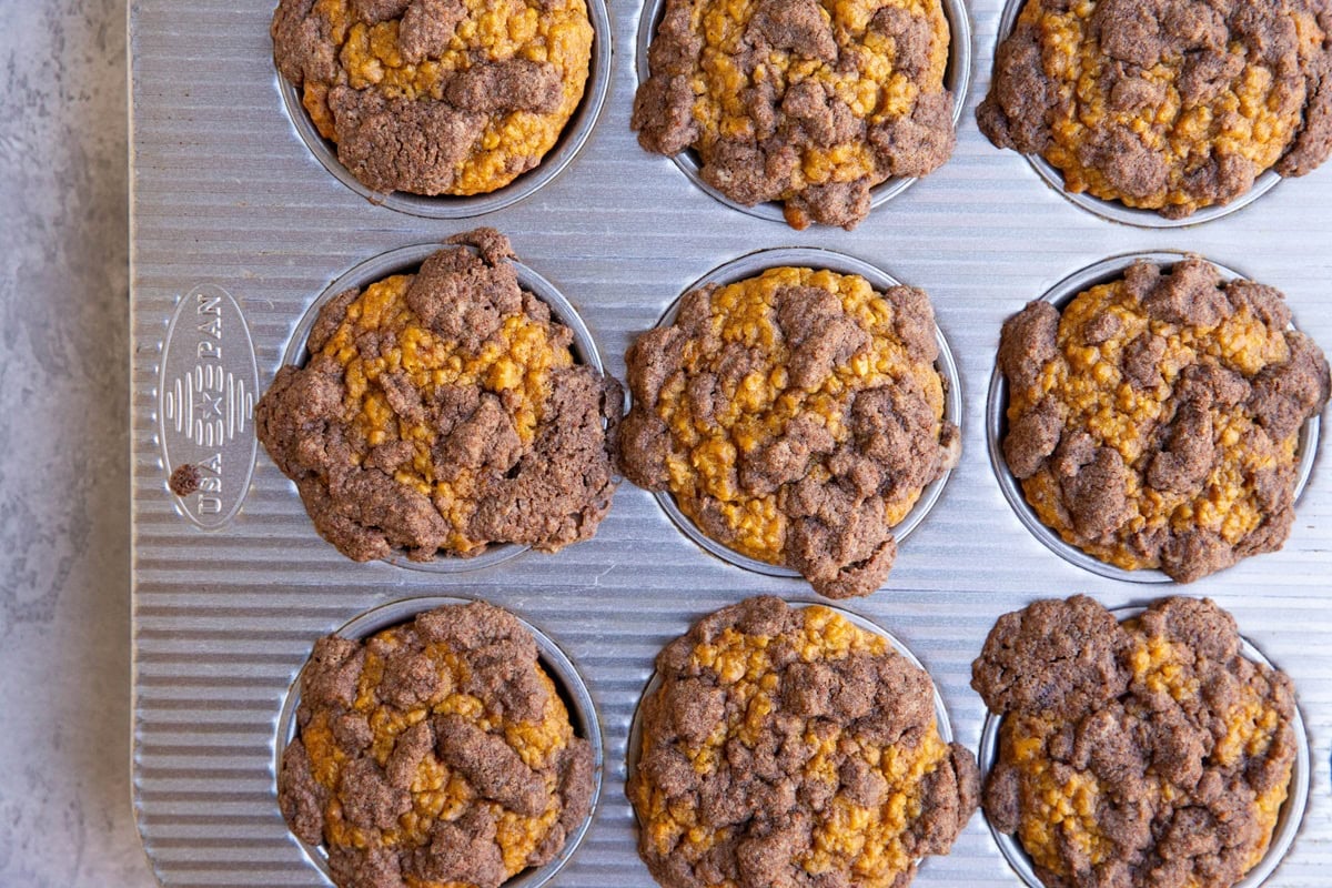 Muffin tray with pumpkin muffins with streusel topping inside, fresh out of the oven.