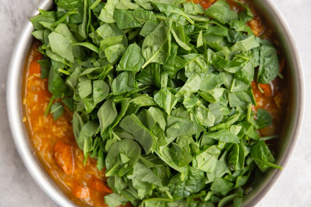 Chopped spinach on top of pumpkin rice sausage mixture. Ready to mix in for wilting.