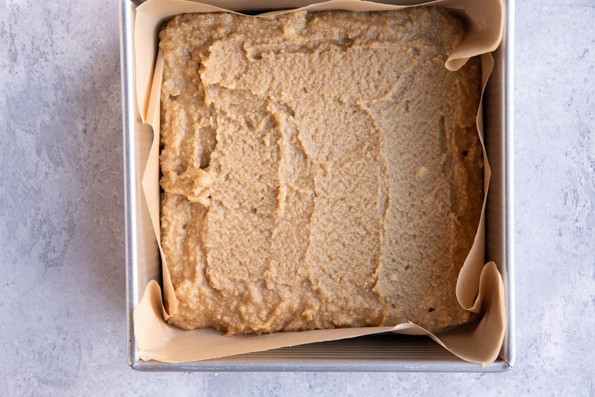 Cake pan with spice cake batter spread inside.