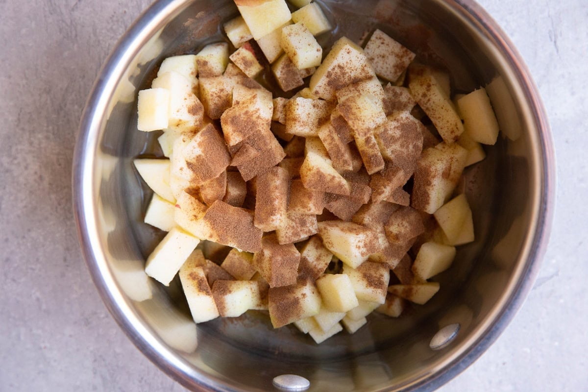 Saucepan with chopped apples, cinnamon and pure maple syrup.
