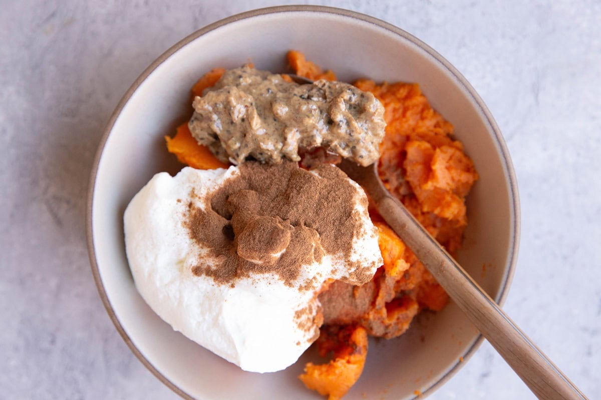 Sweet potato, yogurt, nut butter, and ground cinnamon in a bowl to be mixed together.