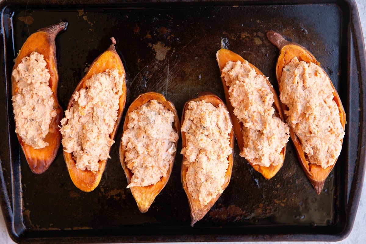 Baking sheet with six sweet potato halves stuffed with yogurt mixture on a baking sheet.